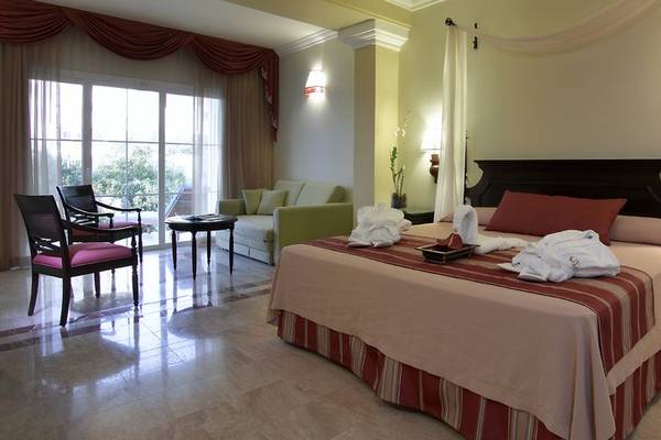 Ein Hotelzimmer im Grand Palladium Jamaica R. & Spa mit einem Bett, zwei Sesseln, einem Tisch und einer Couch.