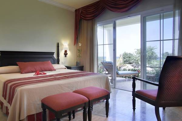 Hotelzimmer im Grand Palladium Jamaica R. & Spa mit Bett, Nachttischen und Balkon.