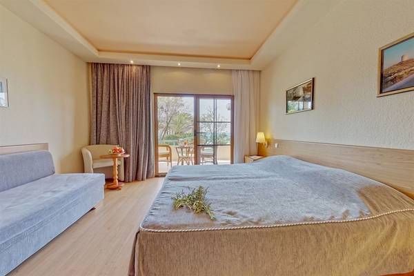 Schlafzimmer im Possidi Holidays Resort & Suites mit Doppelbett, Sofa und Balkon