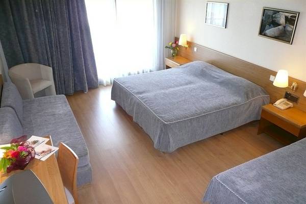 Doppelzimmer im Possidi Holidays Resort mit zwei Betten, Sofa, Schreibtisch und Fenstern.