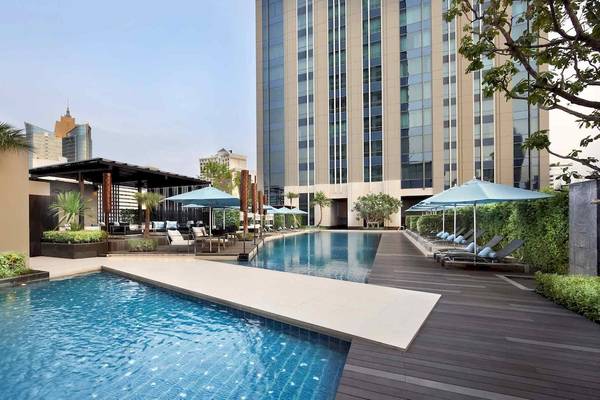 Außenpool des Sofitel Bangkok Sukhumvit Hotels mit Lounges und Sonnenschirmen