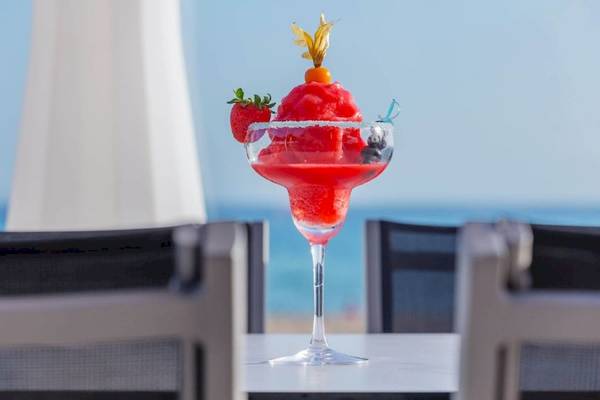 Roter Cocktail in einem Glas mit Blick auf den Strand und das Meer