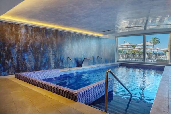 Ein Hallenbad im Aparthotel Fontanellas Playa mit blauen Wänden und Wasserfalldesign.