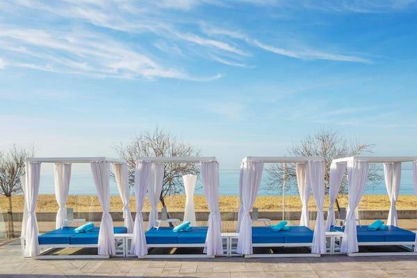 Drei weiße Lounge-Sessel mit blauen Kissen am Strand des Aparthotel Fontanellas Playa.