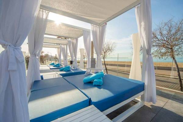 Strandbetten im Aparthotel Fontanellas Playa mit Meerblick und weißen Vorhängen.
