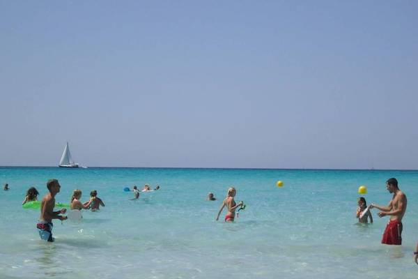 Mehrere Leute spielen im Wasser bei Fontanellas Playa mit gelben Bällen.