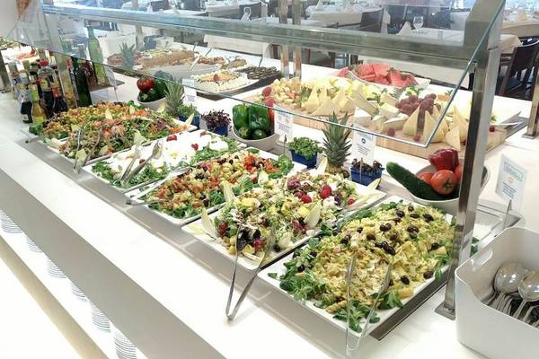 Buffet mit verschiedenen Salaten und Gerichten, darunter Obstsalat, gemischte Salate und Käseplatten.