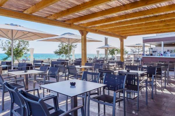 Außenbereich des Aparthotel Fontanellas Playa mit Tischen, Stühlen und Schirmen am Strand