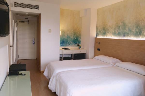 Doppelzimmer im Aparthotel Fontanellas Playa mit zwei Betten, Schreibtisch und moderner Inneneinrichtung.