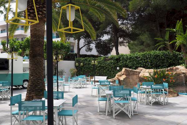 Außenbereich des Cosmopolitan Hotels mit blauen Stühlen und Tischen unter gelben Lampen.
