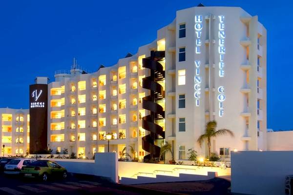 Nachtansicht des Vincci Tenerife Golf Hotels mit leuchtenden Fenstern und einem geparkten Auto davor.