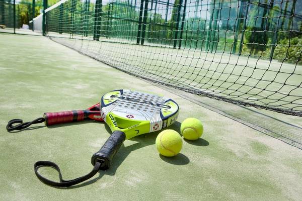 Tennisschläger und Bälle auf einem Tennisplatz neben einem Netz.