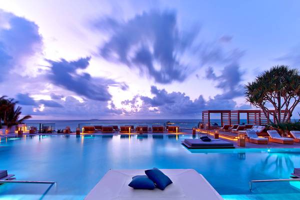 Der Pool des 1 Hotel South Beach bei Nacht mit beleuchteten Liegen und einem Blick auf das Meer.