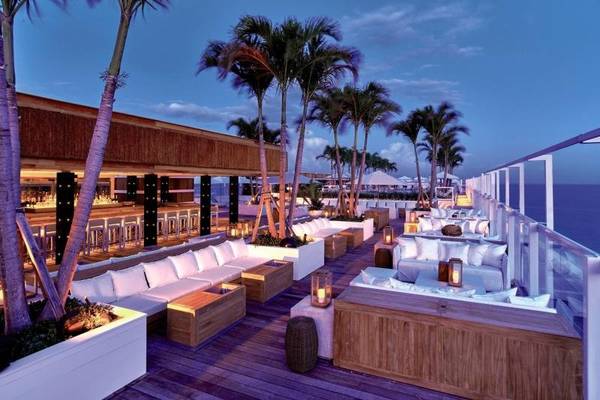 Außenbereich des 1 Hotel South Beach mit Palmen und weißen Sofas auf der Terrasse.