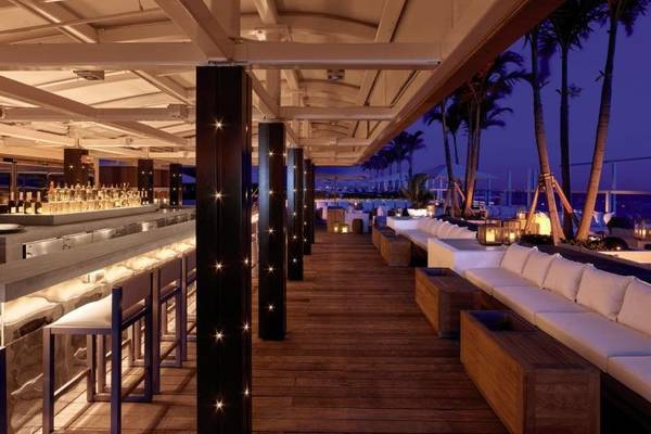 Nachtansicht der Terrasse des 1 Hotel South Beach mit Bar, Sesseln und Blick auf den Ozean