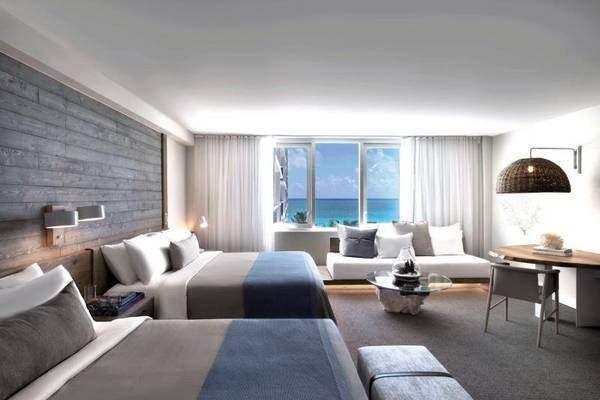 Zwei Doppelbetten und ein Schreibtisch in einer Suite des 1 Hotel South Beach mit Blick auf das Meer.