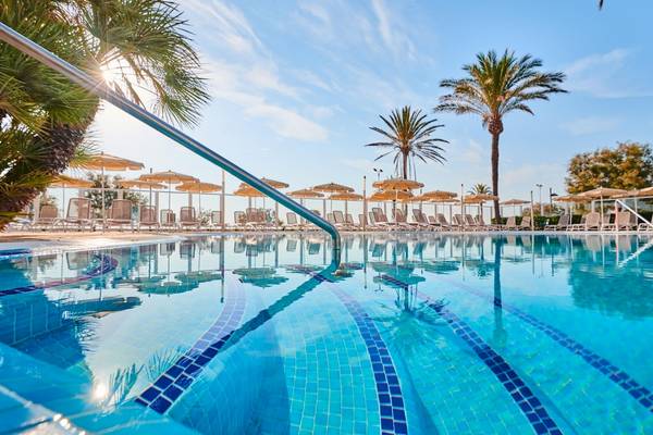 Pool im Hipotels Flamenco Hotel mit Sonnenliegen und Sonnenschirmen an einem sonnigen Tag.