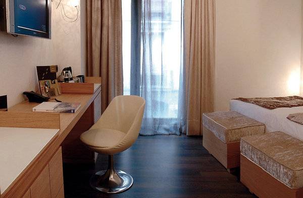 Hotelzimmer im Barcelona Catedral mit Schreibtisch, Stuhl, Betten und Fernseher.