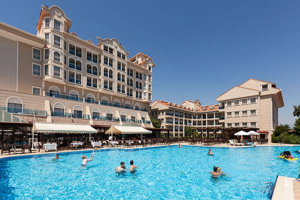 Außenbereich des Sultan of Side Hotels mit großem Pool und Gästen, die schwimmen.