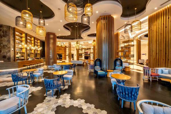 Loungebereich des Sidemarin Kirman Premium Hotels mit blauen Stühlen und Tischen, Holzsäulen und goldenen Pendelleuchten.