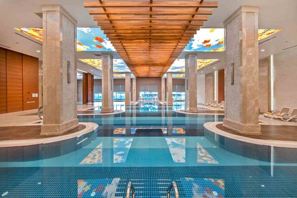 Ein großer Innenpool im Sidemarin Kirman Premium Hotel mit blauem Wasser und bemalten Decken.
