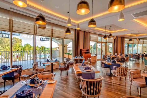 Restaurant im Sidemarin Kirman Premium Hotel mit vollen Tischen und Blick auf den Pool.