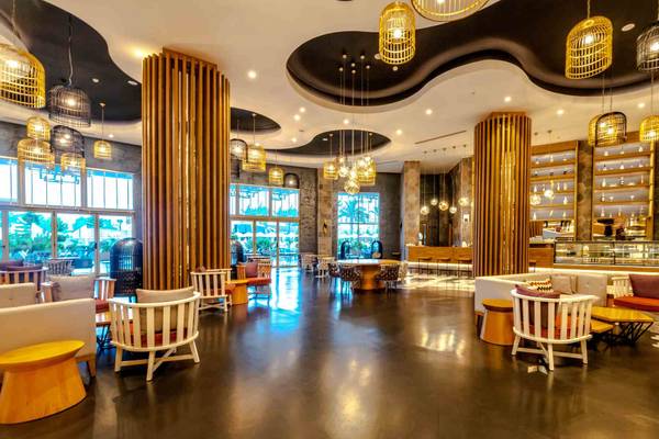 Innenbereich des Sidemarin Kirman Premium Hotels mit Lounge-Stühlen, Tischen und gelben Pendelleuchten.
