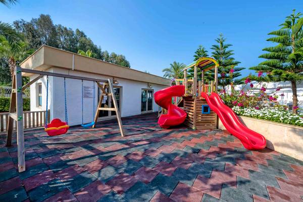 Kinderspielplatz im Hotel Sidemarin Kirman Premium mit roten Rutschen und Schaukeln.