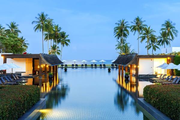 Außenpoolbereich des JW Marriott Khao Lak Resort & Spa mit Palmen und Sonnenliegen.