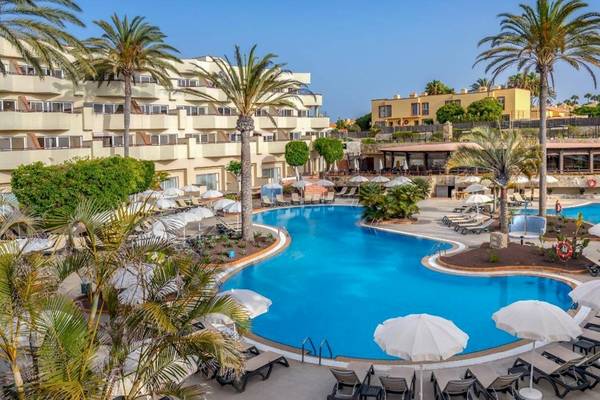 Außenansicht des Pools im Barcelo Corralejo Bay Hotel mit Sonnenschirmen und Liegestühlen.