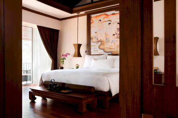 Ein Schlafzimmer im JW Marriott Khao Lak Resort & Spa mit einem großen Bett, weißen Kissen und einer Wandmalerei.