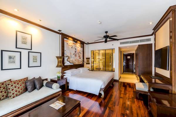 Schlafzimmer im JW Marriott Khao Lak Resort & Spa mit einem großen Bett, einem Couch, Nachttischen und Wanddekoration.