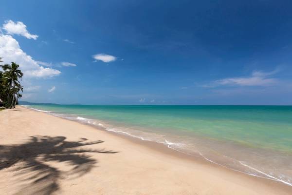 Strand des JW Marriott Khao Lak Resort & Spa mit blauem Himmel und grünem Wasser