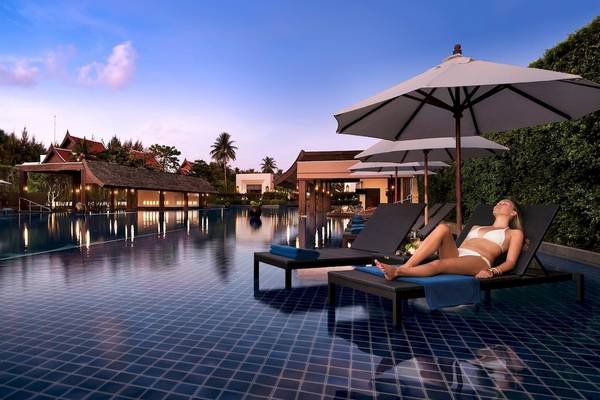 Frau entspannt am Pool unter einem Sonnenschirm im JW Marriott Khao Lak Resort & Spa