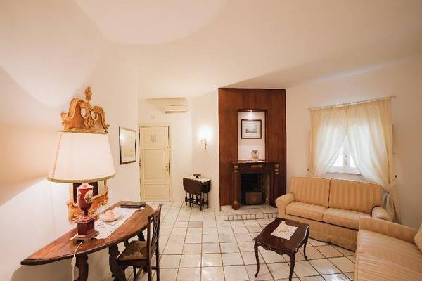Wohnzimmer im Hotel Il Melograno mit Sofas, Kamin, Tisch und Stuhl.