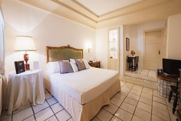 Hotelzimmer von Il Melograno mit einem großen Bett, Kissen, Nachttisch mit Lampe und Fernseher.