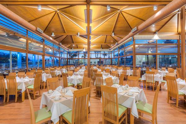 Innenansicht des Restaurants im Blue Lagoon Resort mit vielen gedeckten Tischen und Stühlen, Holzboden und großen Fenstern.