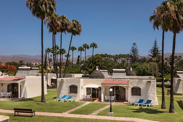 Außenbereich des HD Parque Cristobal Hotels mit Lounge-Stühlen und Palmen.