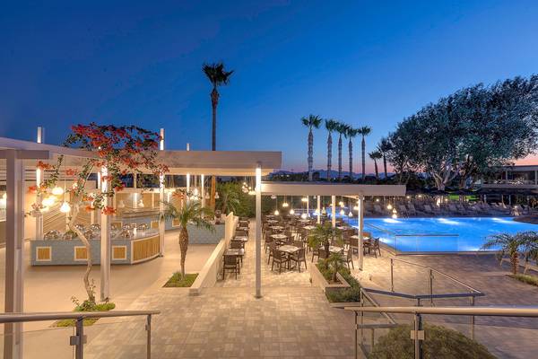 Abendliche Außenansicht des Blue Lagoon Resorts mit Swimmingpool, Außenbar und umliegenden Palmen.