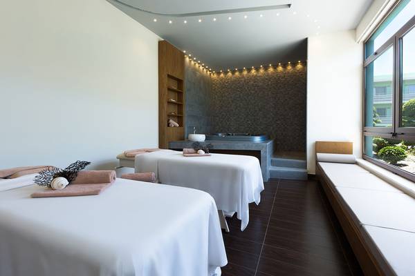 Massageraum im Blue Lagoon Resort mit zwei Massagetischen, Whirlpool und Fenstern.