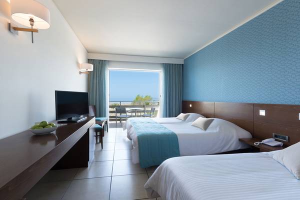 Hotelzimmer im Blue Lagoon Resort mit drei Betten, Fernseher, Balkon und Meerblick.