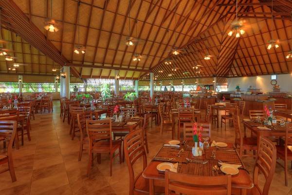 Innenansicht des Restaurants im Fihalhohi Island Resort mit vielen Holztischen und Stühlen.