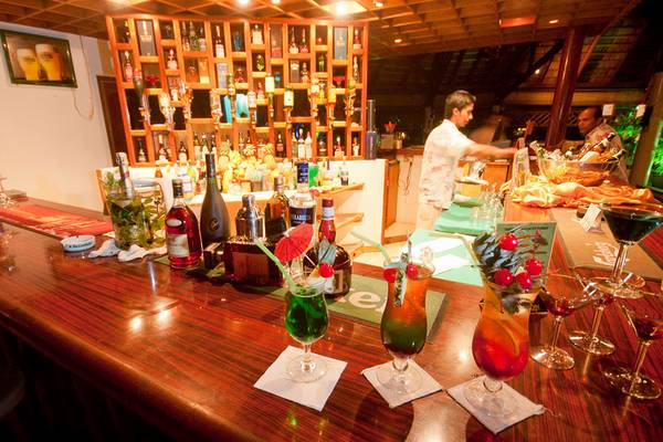 Bar im Fihalhohi Island Resort mit Cocktails, Flaschen und Barkeeper.