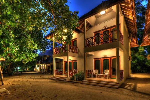 Nachtansicht des Fihalhohi Island Resorts mit zweistöckigen Gebäuden, Balkonen, und Gartenlandschaft.