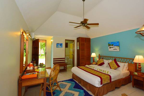 Ein modernes Hotelzimmer mit Doppelbett, Schreibtisch, Stühlen, Deckenventilator und Wanddekorationen.