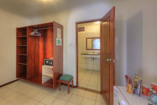 Innenansicht eines Hotelzimmers im Fihalhohi Island Resort, mit Schrank, Safe und offenem Badezimmer.