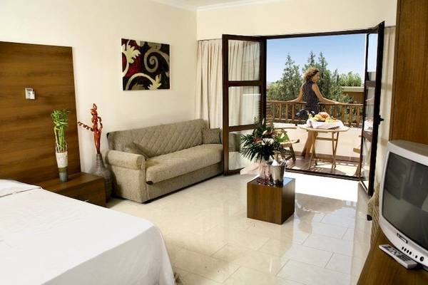 Hotelzimmer mit Sofa, Tisch und Balkon mit Blick auf die Landschaft.