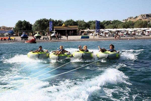Vier Kinder ziehen Boote im Wasser hinter einem Boot her