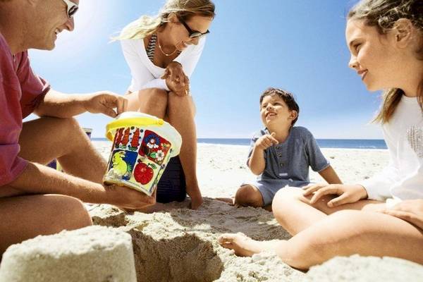 Familie im Costa Lindia Beach Resort am Strand mit Sandburg und Eistüte