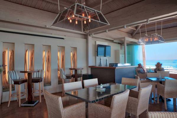 Innenbereich der Bar im Acharavi Beach Hotel mit Blick auf das Meer und Gästen, die sitzen.